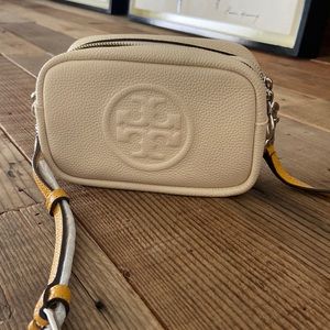 Tory Burch cream colored bag. Unique orange strap, and two zipper compartments.